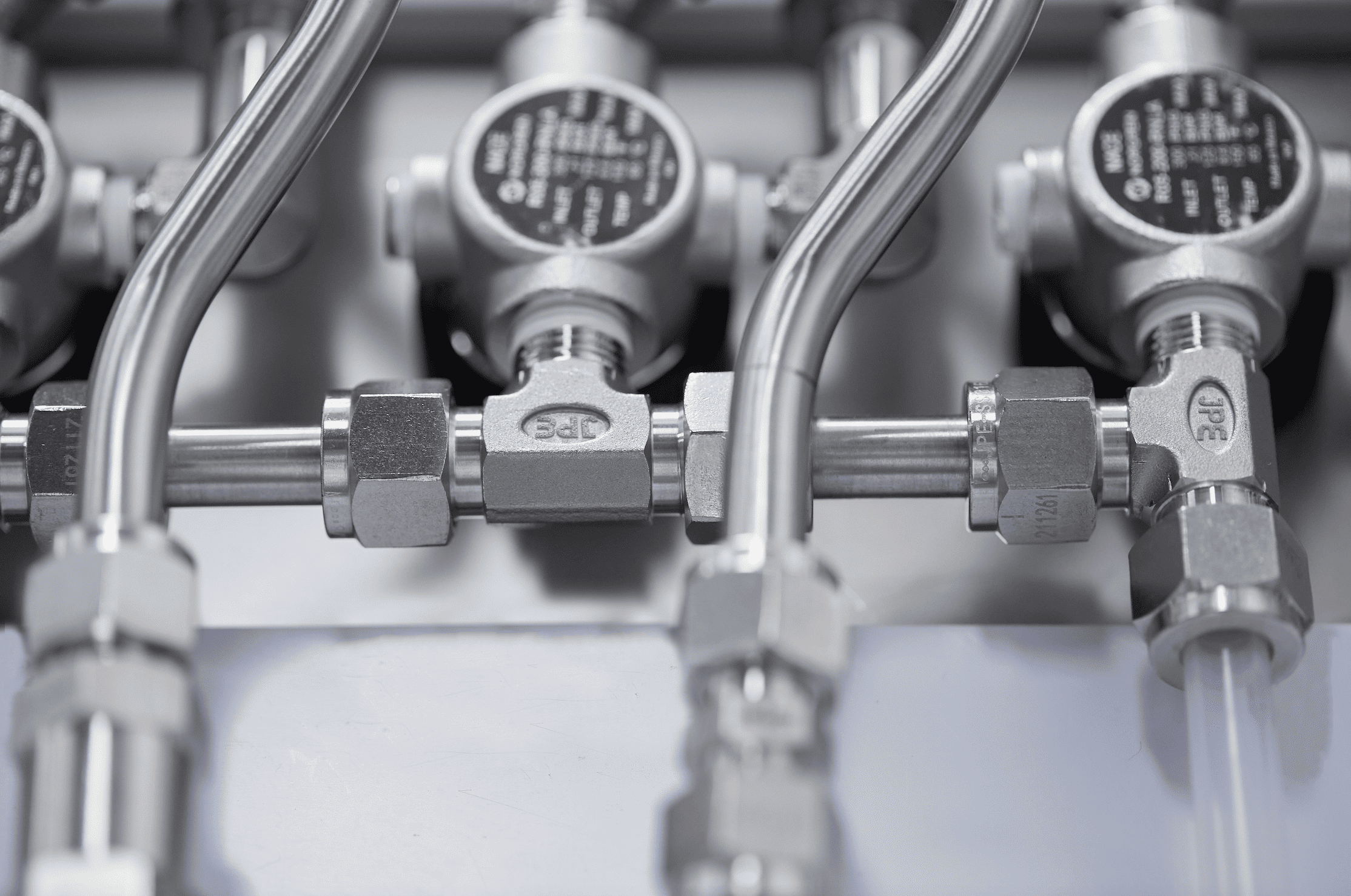 Close-up of JPE stainless steel tube fittings and valves assembled in a high-pressure pipeline system for hydrogen, semiconductor, and instrumentation control applications.