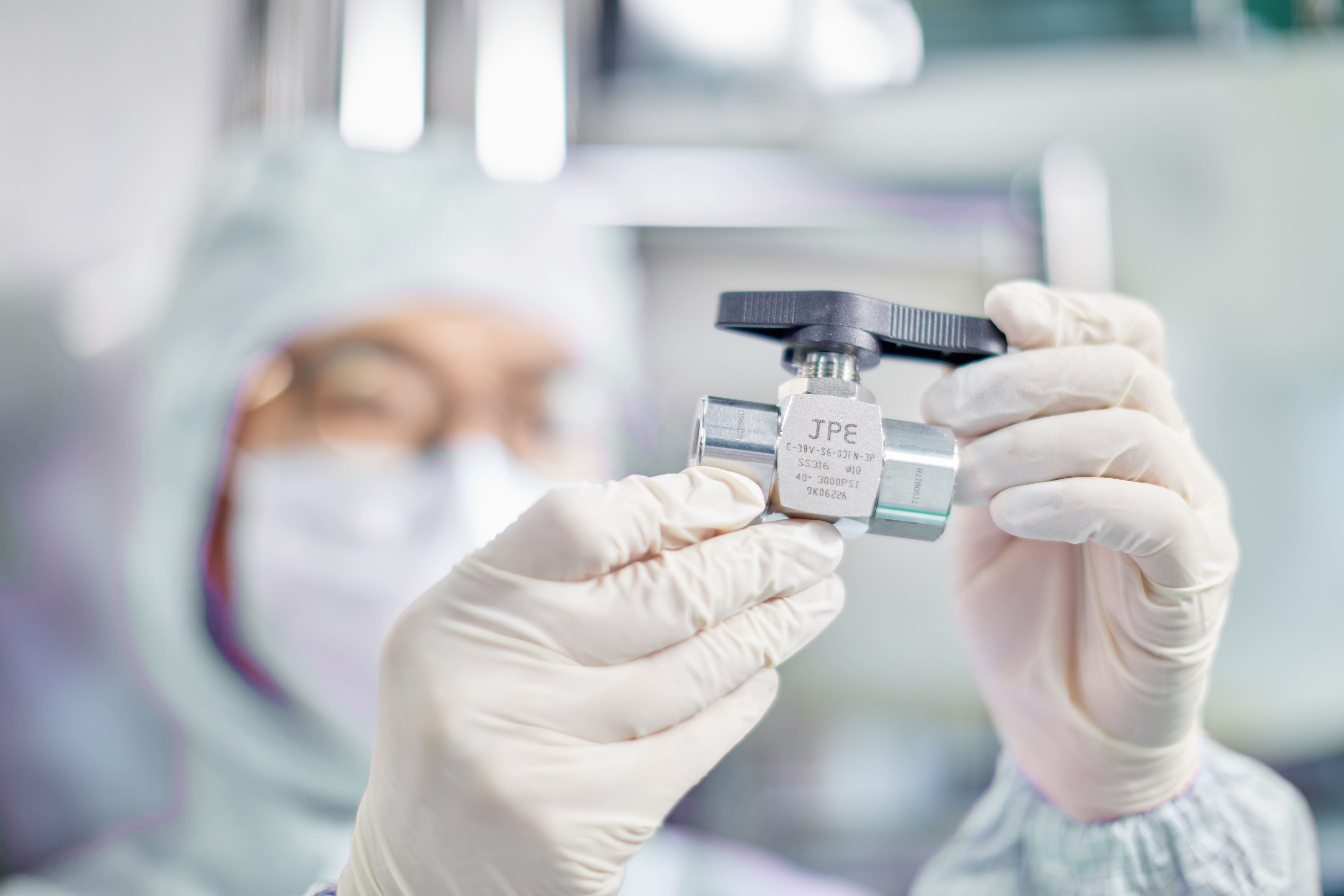 JPE工程师在无尘室中检测不锈钢高压阀门,确保氢能与半导体系统的密封与安全性能。