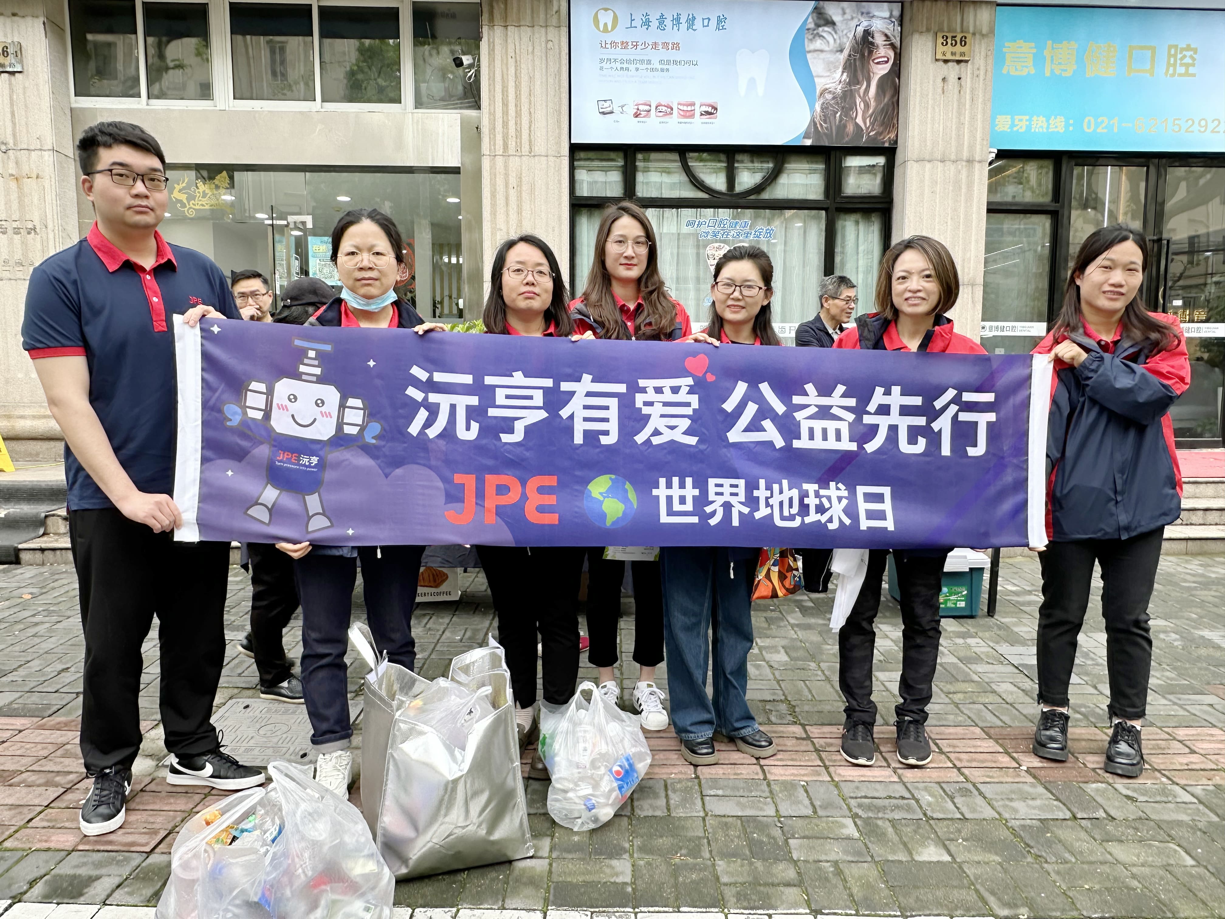 JPE Kunshan team at an Earth Day community environmental event in Shanghai’s Changning District, holding a banner and displaying sorted recyclable materials.