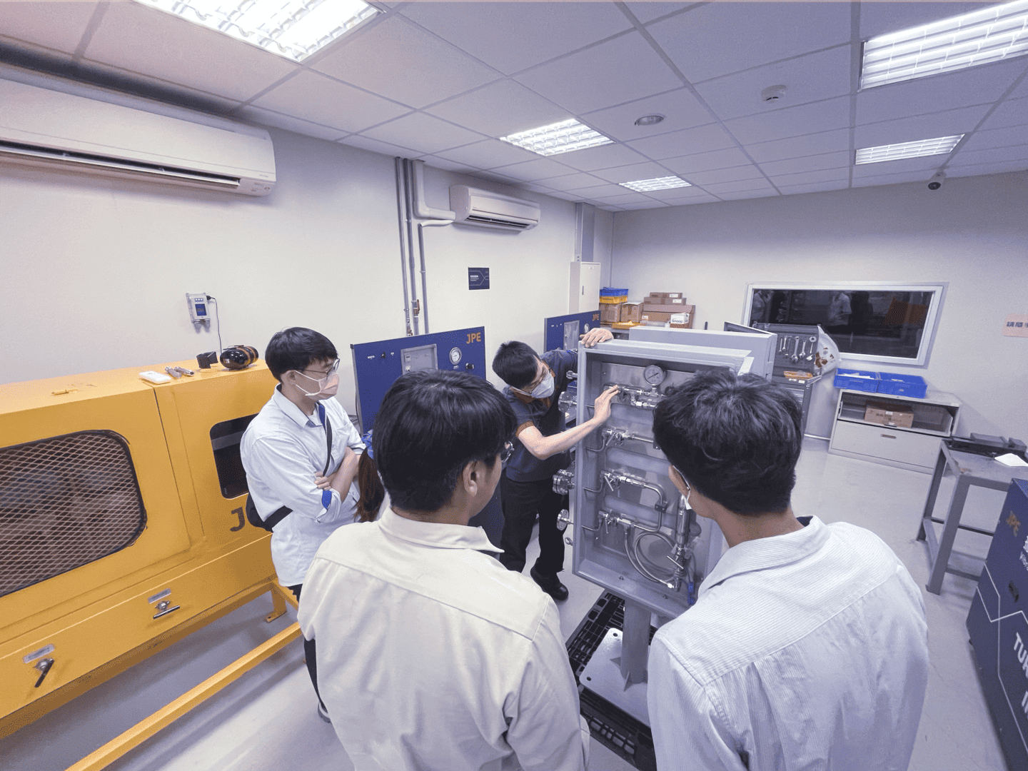 A JPE engineer demonstrating the functions of the petrochemical sampling system while customers observe closely.