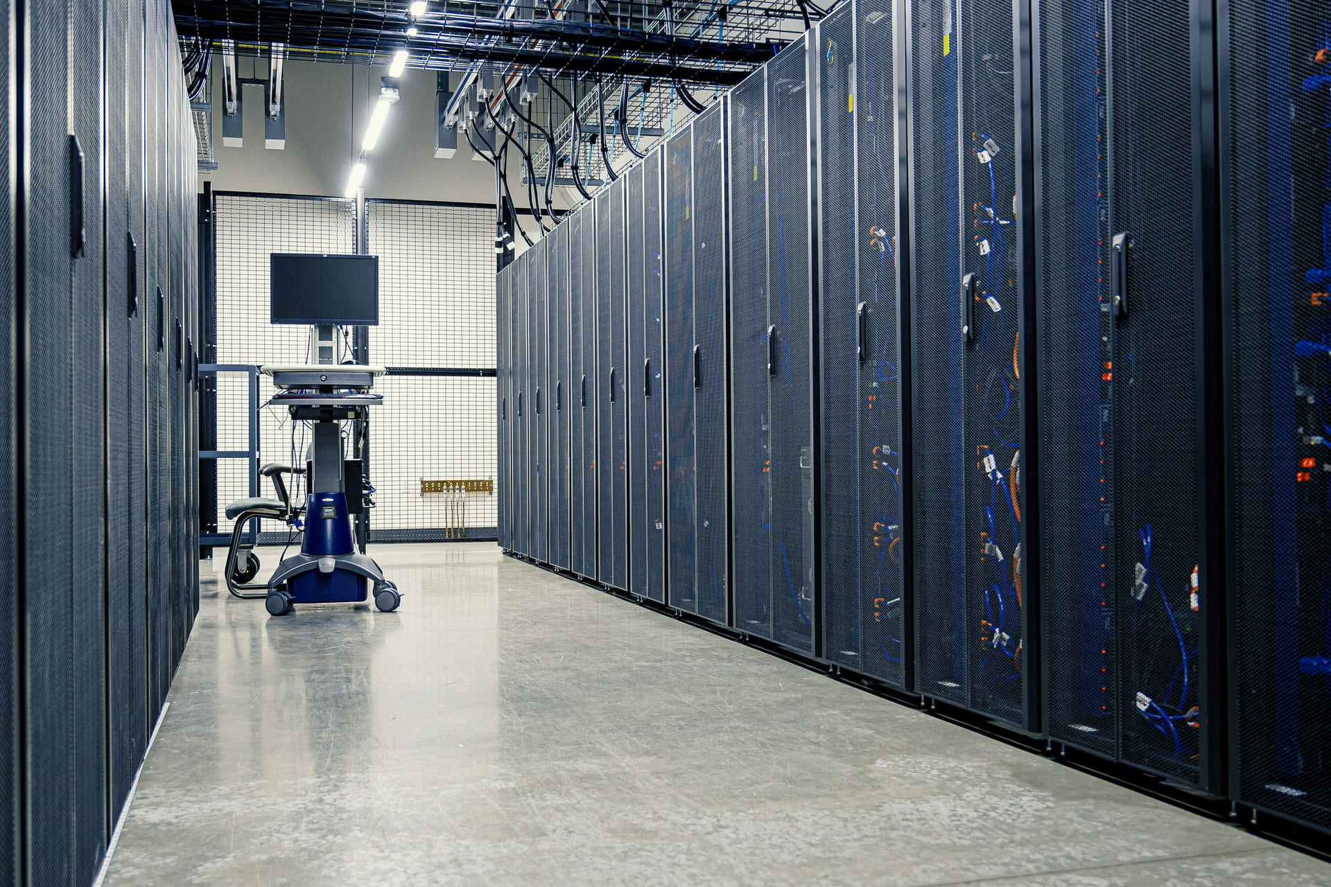 Modern data center aisle with server racks and overhead cable trays, representing HPC and liquid-cooling system deployment.